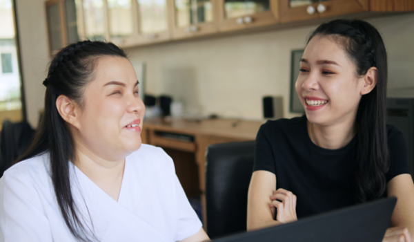 Two Women Sitting and interacting with a computer screen.