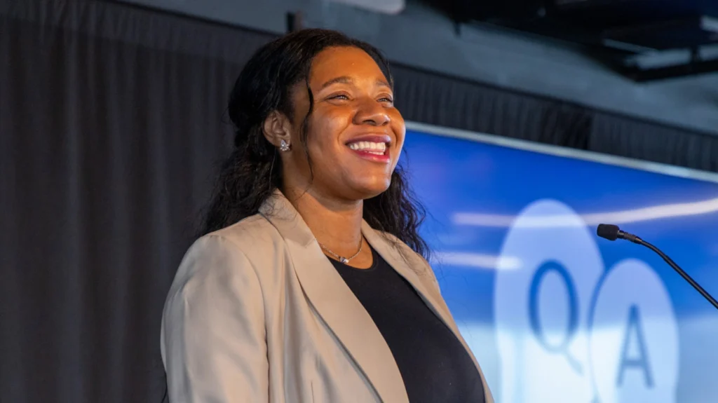 Dr Moya Hill smiling while speaking at a podium