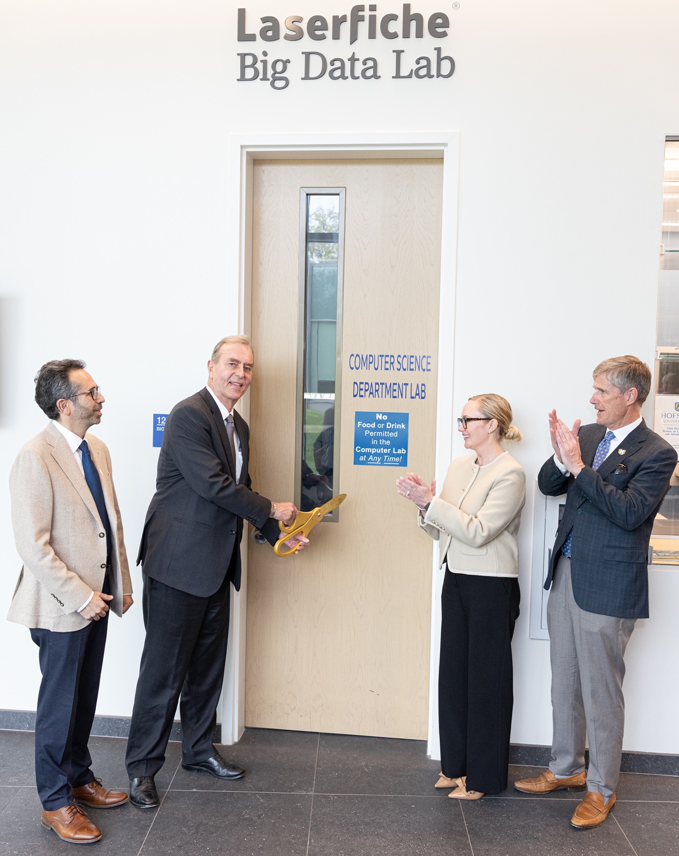 Laserfiche Chairman Chris Wacker cuts the ribbon at the grand opening of the Laserfiche Big Data Lab at Hofstra University, surrounded by applauding university officials.
